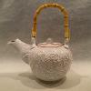 Stoneware teapot with cane handle and carved Peony flower and leaves.