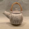 Stoneware teapot with cane handle, slit and expanded exterior.