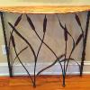 Console table of worm-eaten pine, wrought iron cattails and lizard climbing up right back leg.
